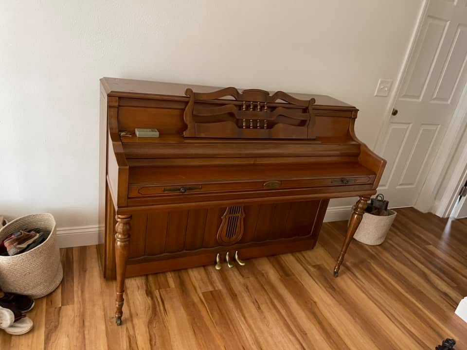 Upright wooden piano in living room with hardwood flooring
