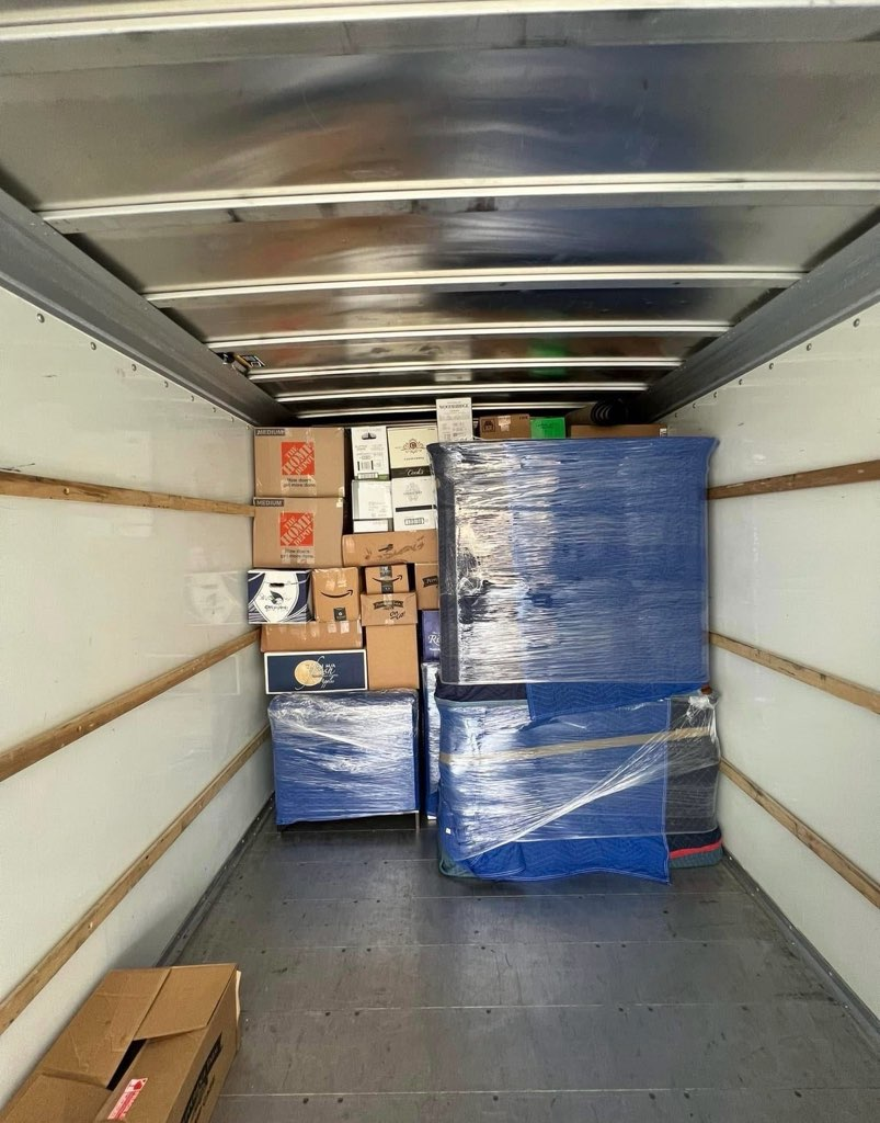 Interior of moving truck loaded with wrapped furniture and cardboard boxes